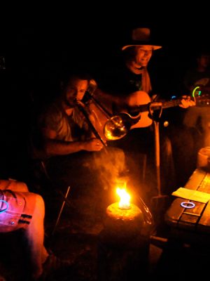 Photograph of musicians playing around fire